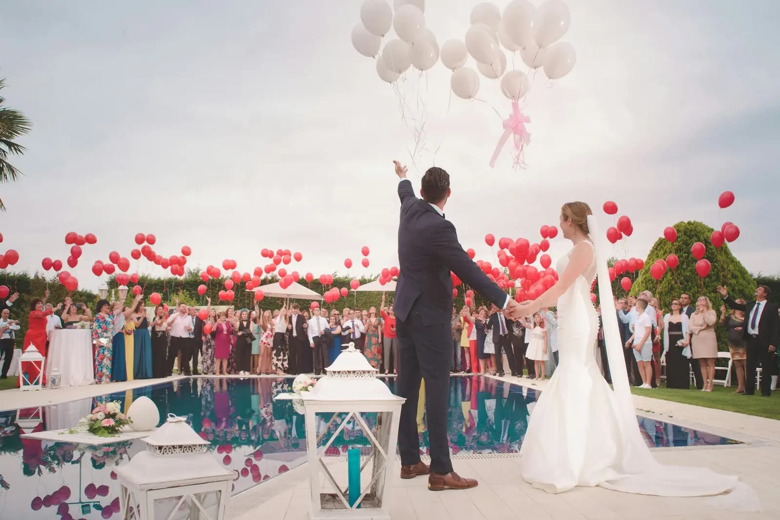 Poolside wedding ceremony with guests and balloons